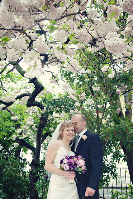 groom smelling bride's temple underneath a blossoming tree at Islington wedding