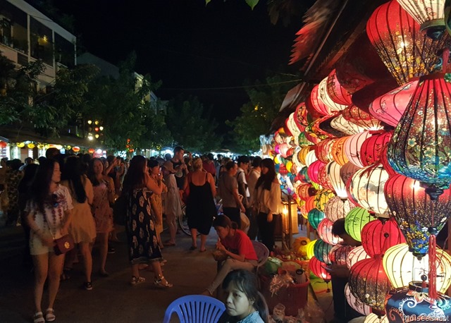 Night market with many stalls and colourful lanterns for sale.