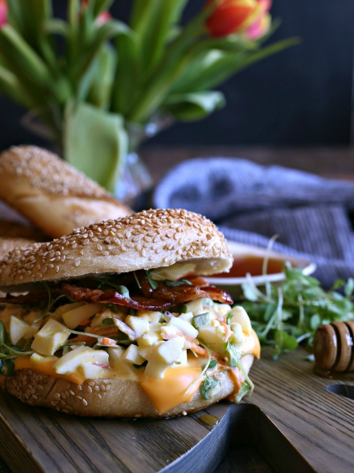 Recipe for an egg salad sandwich on a bagel, topped with bacon roasted with honey.