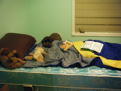 Alfie's standing next to a bed and resting his chin on the sleeping bag that is on it.