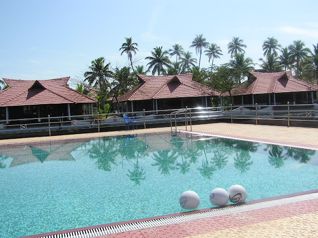 Attractive swimming pool inside the Lake View Resort in Alleppey, with cottages next to the water