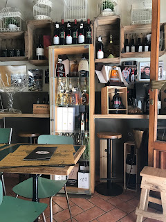 foto de pequena taberna com mesa para comer prato do dia e panini para levar, vinhos disponíveis