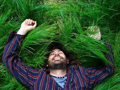 man looks relaxed as he lies down on green grass