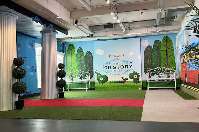 The outside of The 100 Story Hotel Exhibition has a pretend garden area and columns