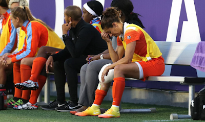 Carli Lloyd sits on the bench with ice on her knee during Saturday’s match in Orlando