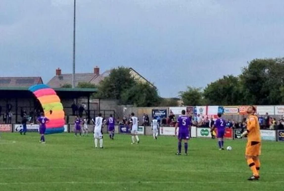 A parachutist lands on the pitch during the match between Salisbury City and Chester