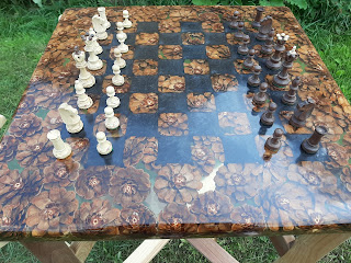 A handmade chess table made from clear resin and pine cones.