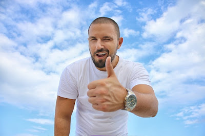 man in white shows his thumbs up