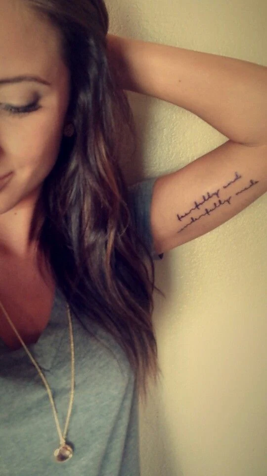 chica sonriendo con tatuaje de frase en el brazo
