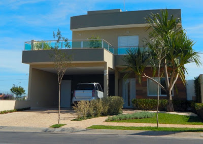 As platibandas sobre os beirais na fachada desta casa compõem linhas suavemente curvadas. A laje sobre a garagem é um grande terraço da suíte do casal.