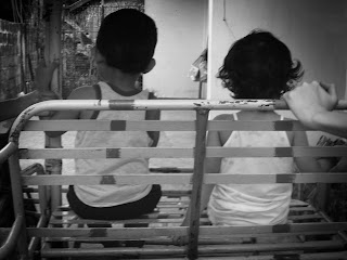 The backs of a little boy and a little girl sitting together.