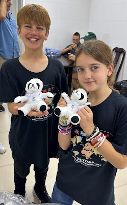 Two children holding stuffed panda bears to give to pediatric patients.