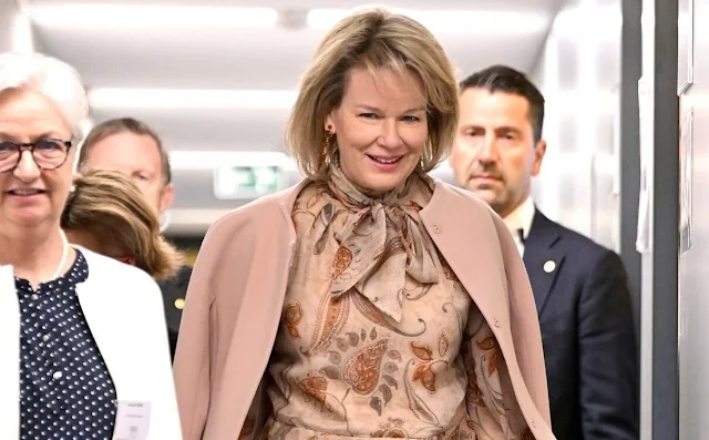 Queen Mathilde wore a beige paisley silk blouse by Etro, and rose suit, blazer, jacket and trousers, by Natan. Princess Elisabeth