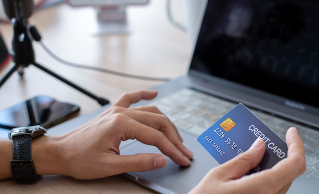 A person writing his credit card numbers on a laptop to pay online