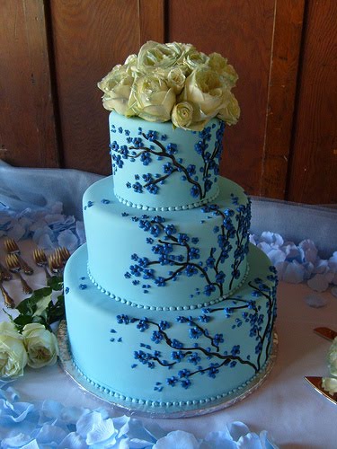 Round three tier blue wedding cake with blue cherry blossoms decorating the