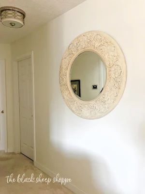 Large round mirror hanging in hallway.