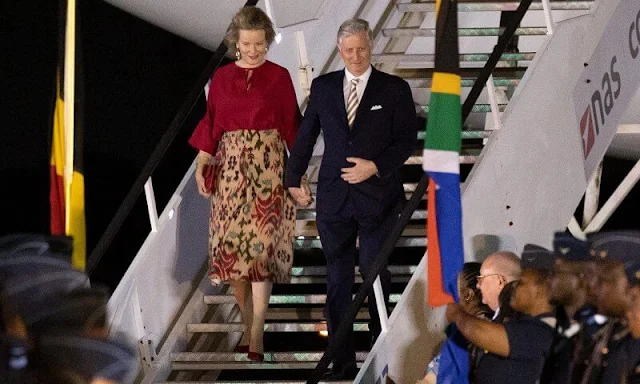Queen Mathilde wore ared silk blouse by Natan. The Queen wore a print silk skirt by Natan. Giorgio Armani navy clutch and red pumps