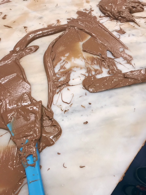 Melted chocolate being tempered with a spatular