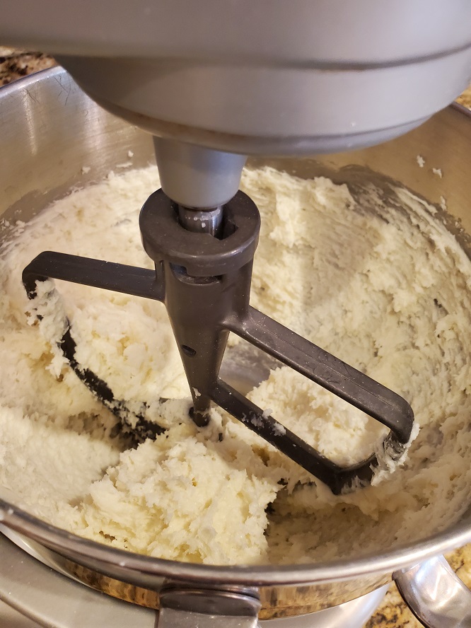 this is the candy being mixed in an industrial mixer bowl with coconut cream cheese and butter