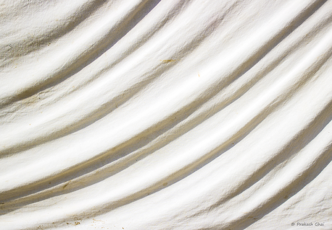 A Minimalist Photo of curves in repetition formed by light and shadow combination on a Creased white cloth 