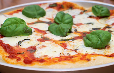 Una pizza Margarita que lleva tomate, mozzarella y varias hojas de albahaca