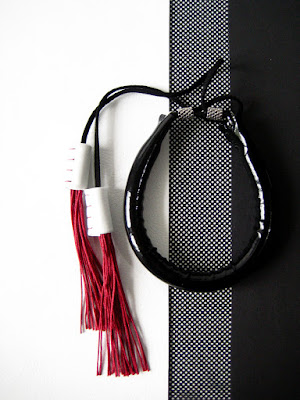 Bracciale ecopelle nero lucido e nappe.