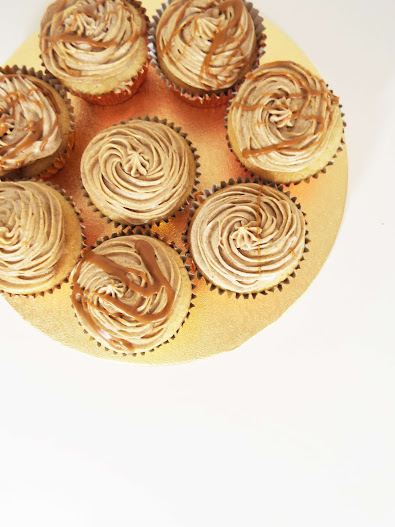 A birds eye view of the caramel coloured biscoff cupcakes, with biscoff drizzled over every other cupcake. All sat proudly on a gold cake stand.