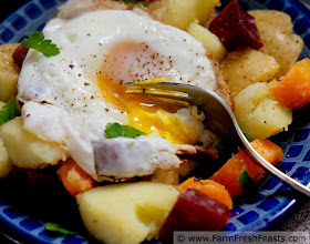 Image of a plate of roasted beets, carrots, and potatoes on a bed of spinach topped with a fried egg.