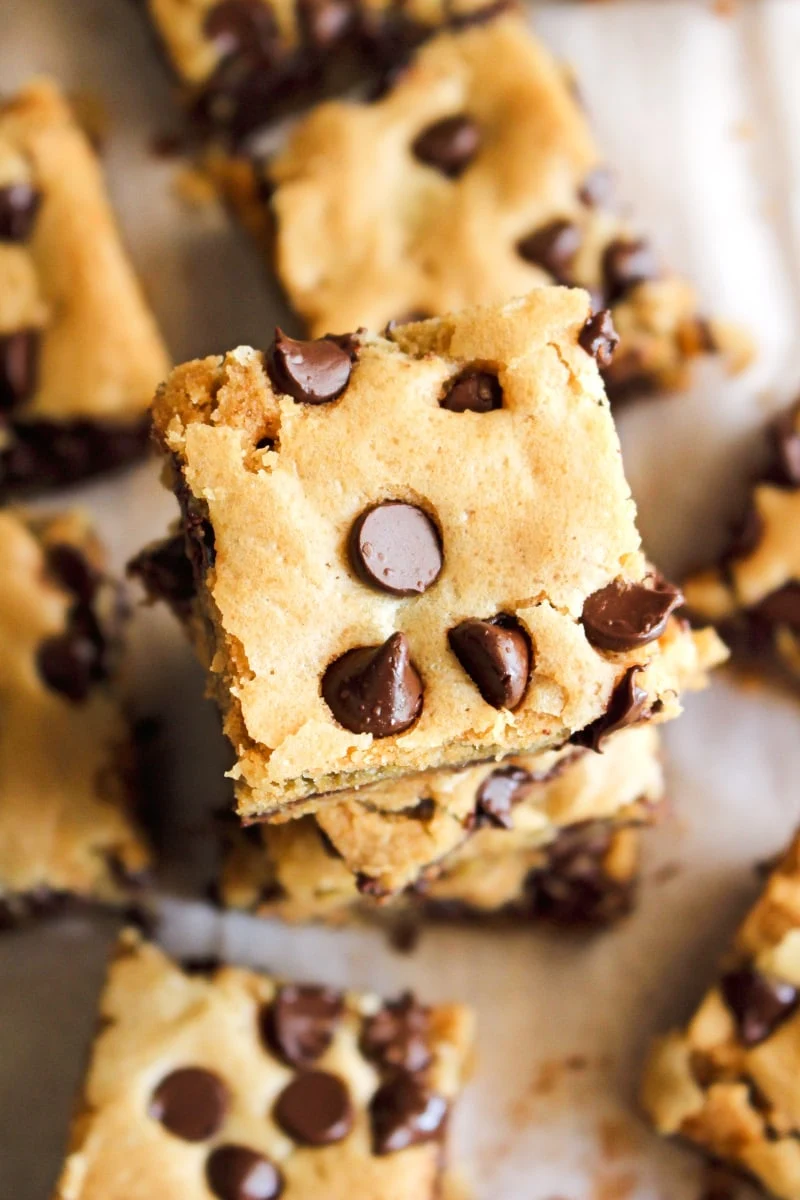 Top view of brown butter cookie bars squares stacked on a piece of parchment paper.