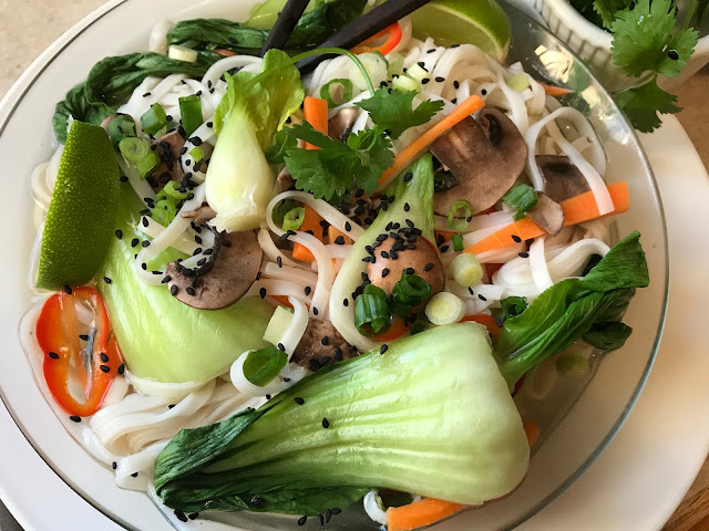 A bowl of Pho broth with noodles and vegetables