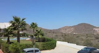 the swimming pool in our gardens with palm trees and the mountains visible behind it