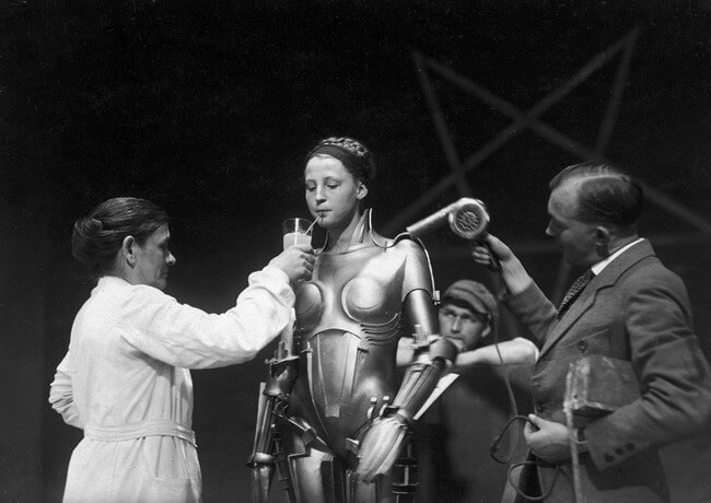 60 Iconic Behind-The-Scenes Pictures Of Actors That Underline The Difference Between Movies And Reality - The actress inside the Maria robot getting a reboot on the set of Fritz Lang’s Metropolis.