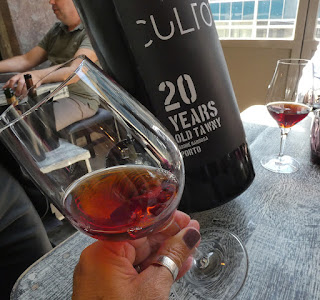 uma mão de mulher segurando um coo de vinho do Porto com garrafa de vinho com rótulo Culto Tawny 20 anos