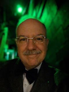 bald man with mustache, blurred green background