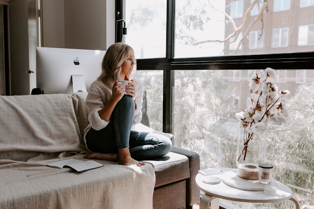 woman looking out of window while social distancing