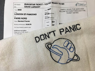 Picture of train ticket and a towel with "Don't panic" written on it.