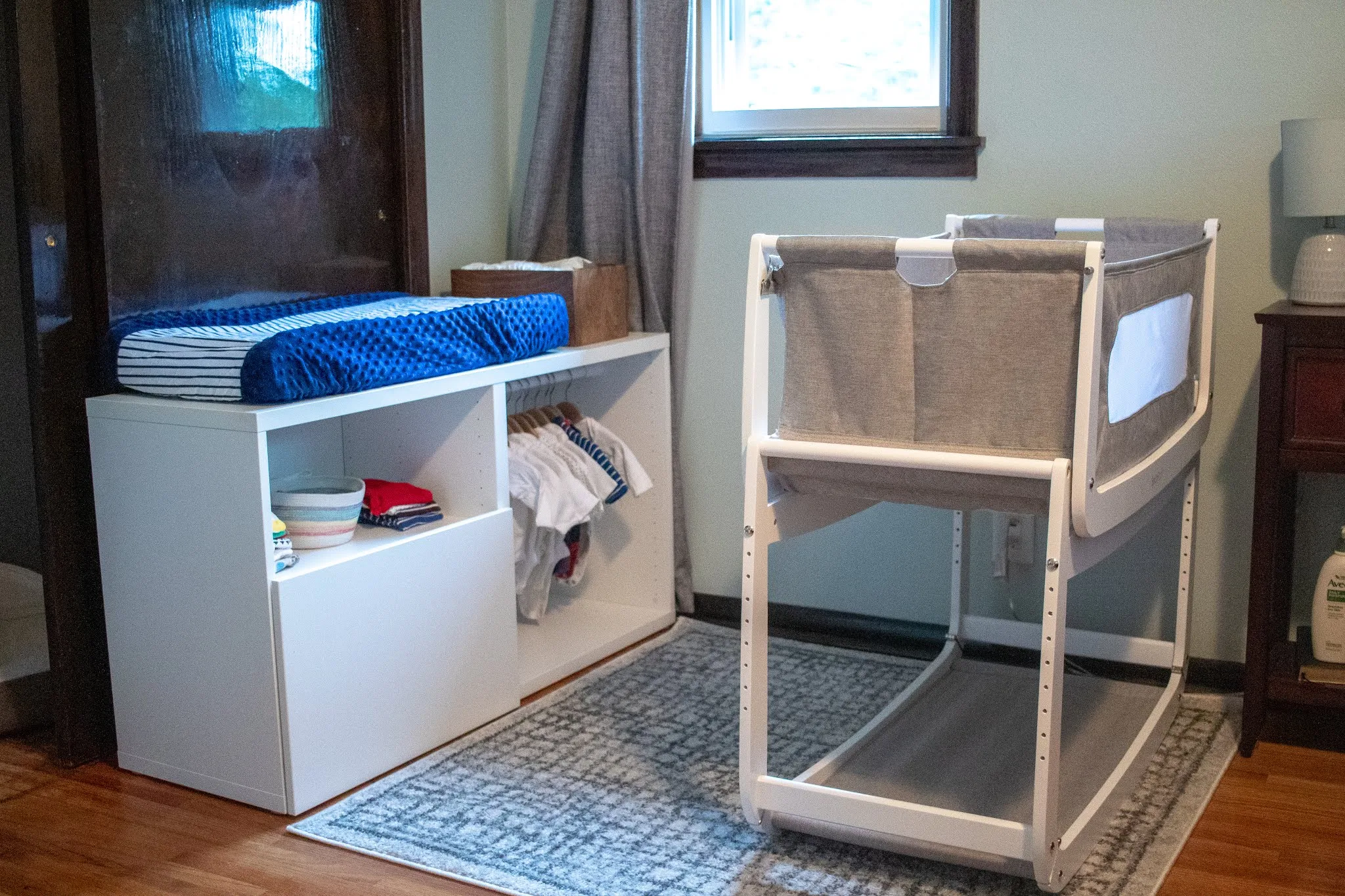 A Montessori baby space designed for a newborn including a Snuzpod basinet, a low changing table, capsule wardrobe, and storage.