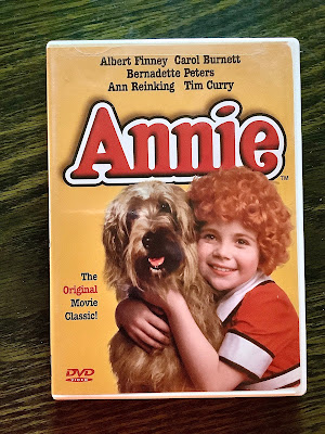 The DVD of Annie shows curly red-haired Annie hugging the dog sandy.