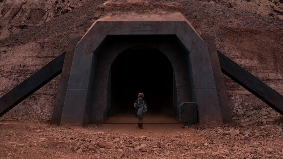 Remmy at the gates leading out of the force field protected valey on Mars in Settlers (2021) movie