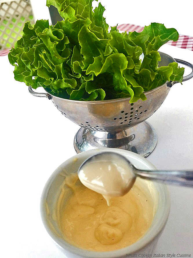 this is a colander with lettuce in the background and a bowl of homemade thousand island dressing with a spoon