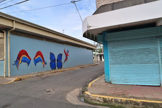 Blue building with colorful bird wings, butterfly wings and parrot in Puriscal.