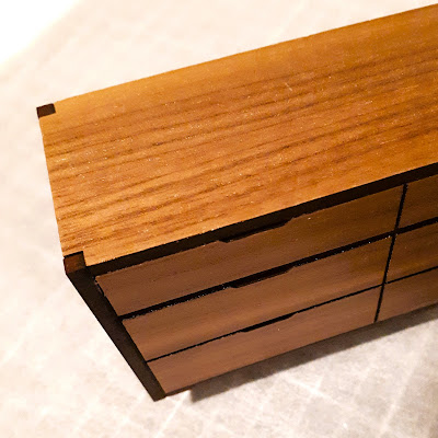Top of a one-twelfth scale mid-century modern dresser kit, with tabs from internal pieces showing through on the outside corners of the top.