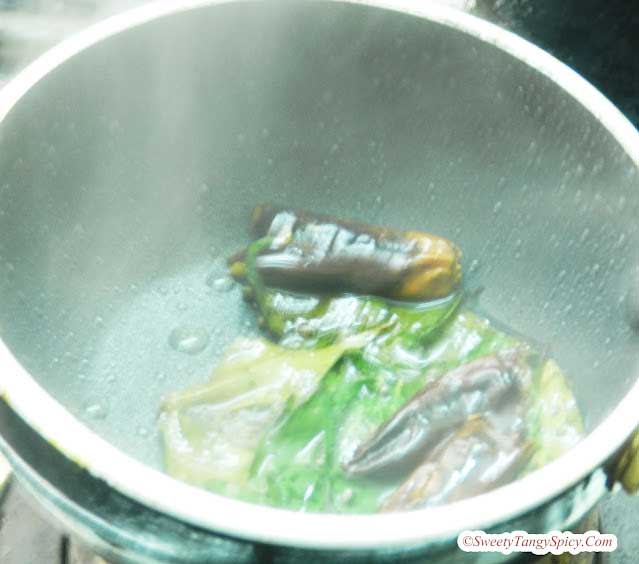 Tempering process: heating oil, mustard seeds spluttering, adding curry leaves and red chilies, and quick stirring.