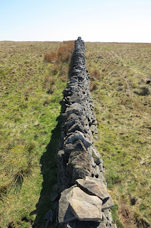 A picture looking along the top of a dry stone wall as it stretches into the distance.