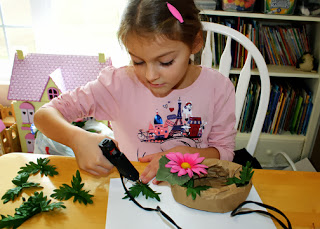 Tessa remembered a sack of abandoned faux flowers in our basement that she decided to use to craft her "All About Me" nest. She learned how to use a hot glue gun at the fall camporee she attended a couple of weeks ago, so I let her have at it. This was her first time doing something like this, so I provided some pointers on floral arrangement along the way.