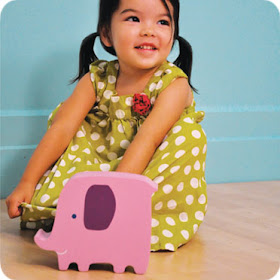 wood bank shaped like an elephant, with a little girl