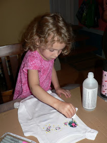 child using a dropper to squirt rubbing alcohol onto DIY tie-dyed shirts