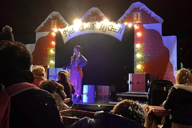 A stage saying Mrs Claus' Kitchen with presents and an elf