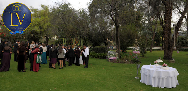 invitados de pie y mesero los atiene en los jardines