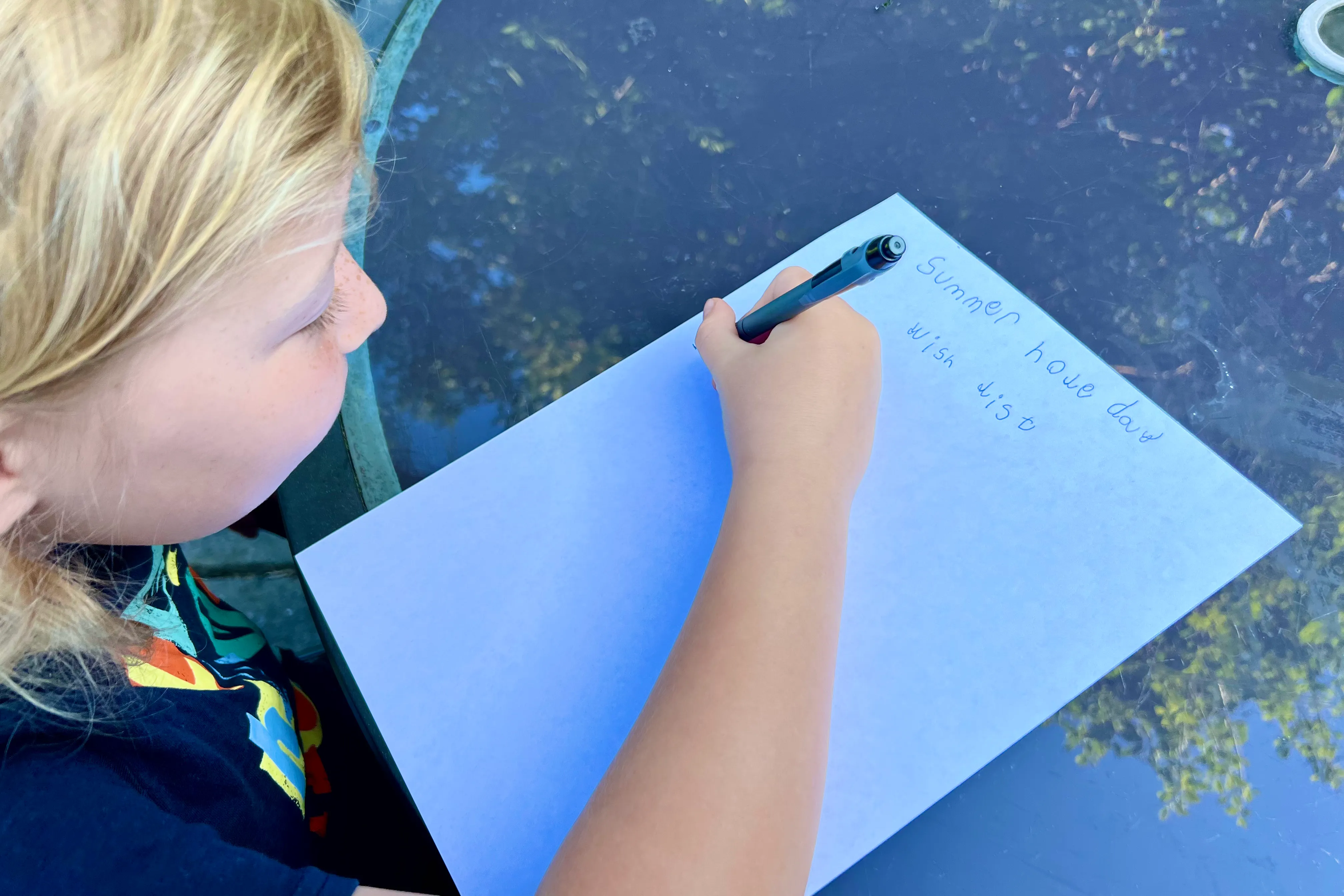 A child writing a wish list of ideas for what to do over the summer holidays in Essex